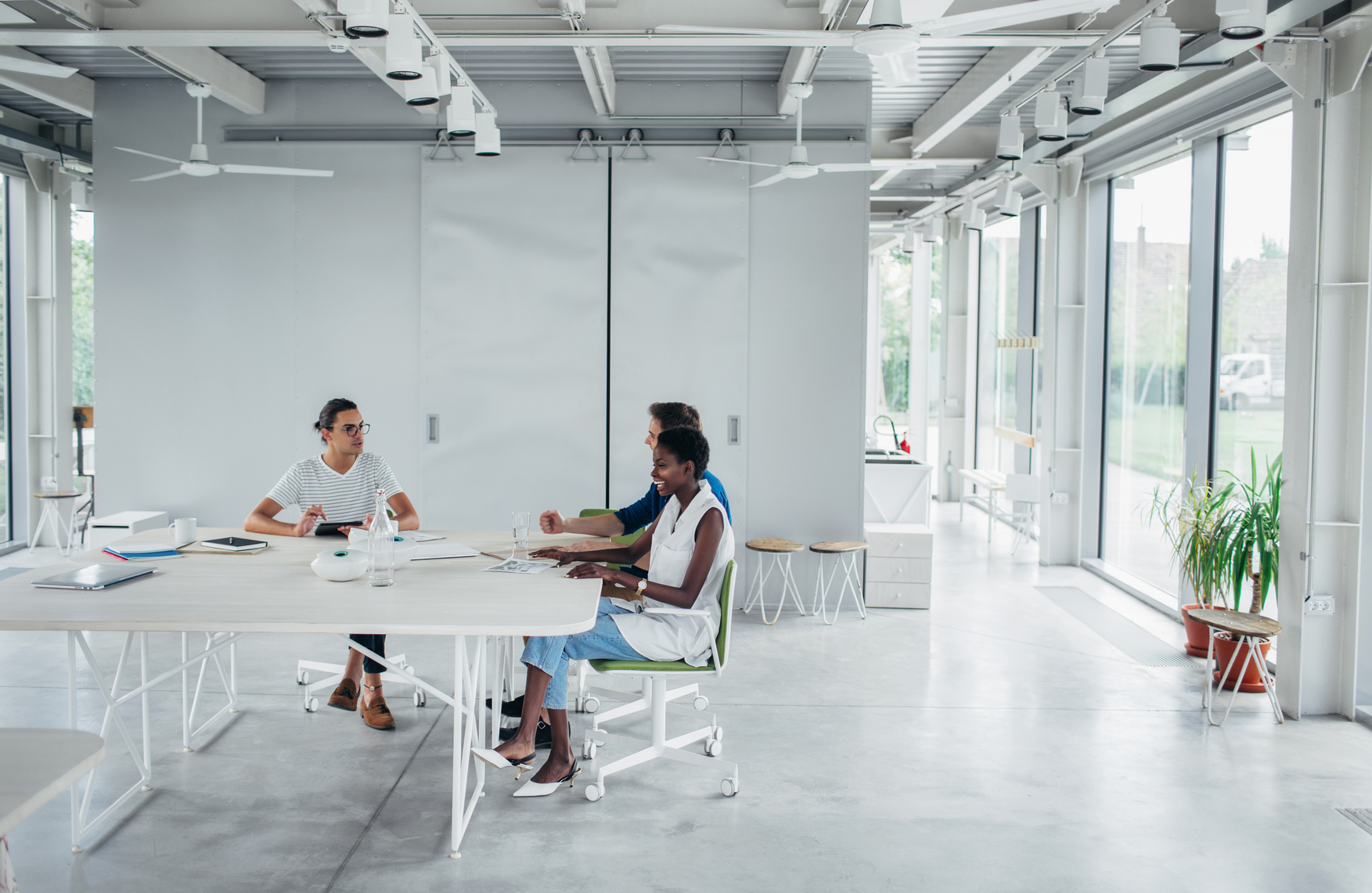 three persons sitting on the table in large white room